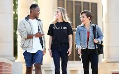 Three students smiling and talking walking outside of Moulton Tower.