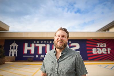 Adult Learner student standing in front of South mural.